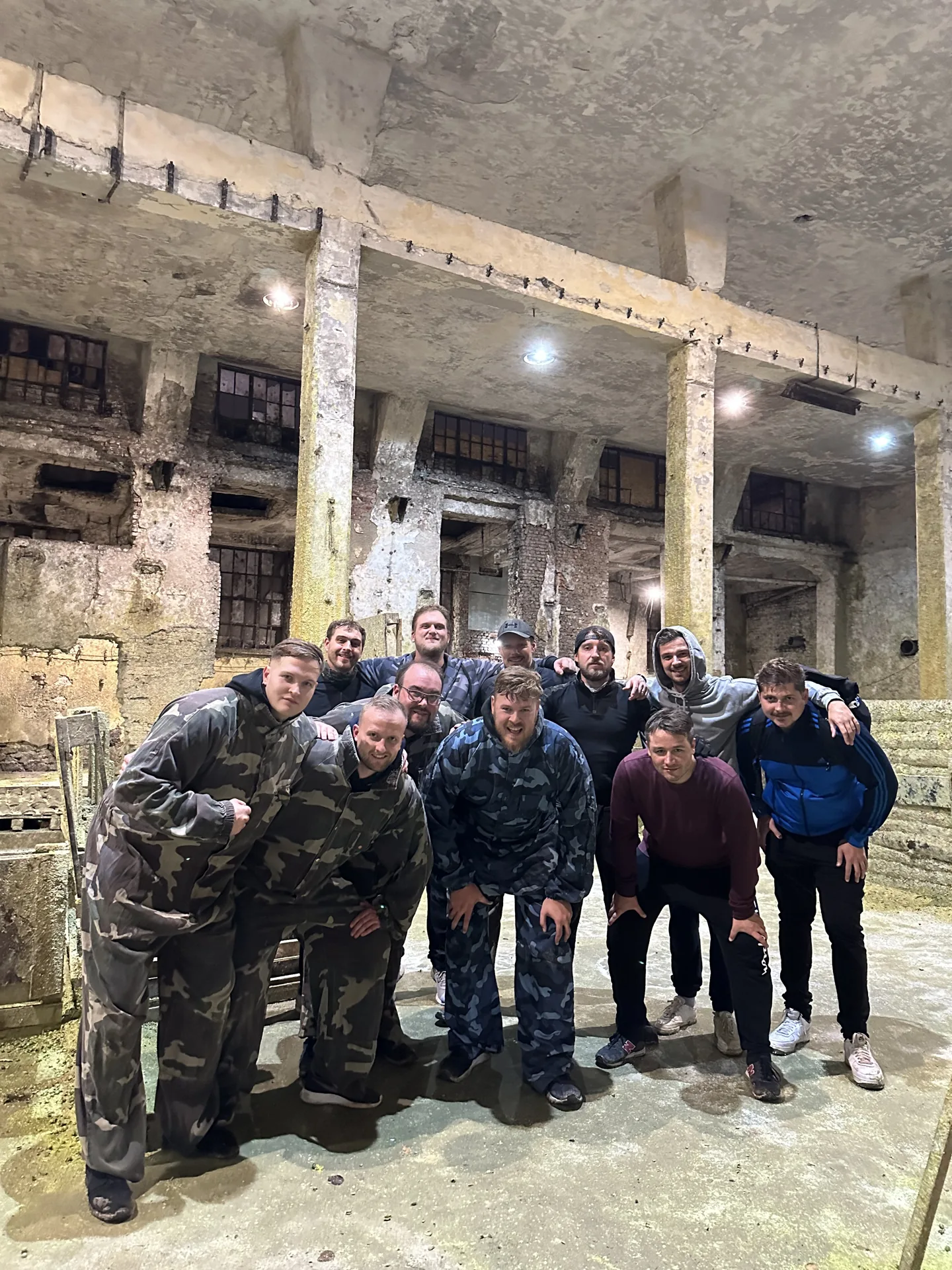 Group of friends in camouflage paintball overalls in the indoor paintball field near Sofia